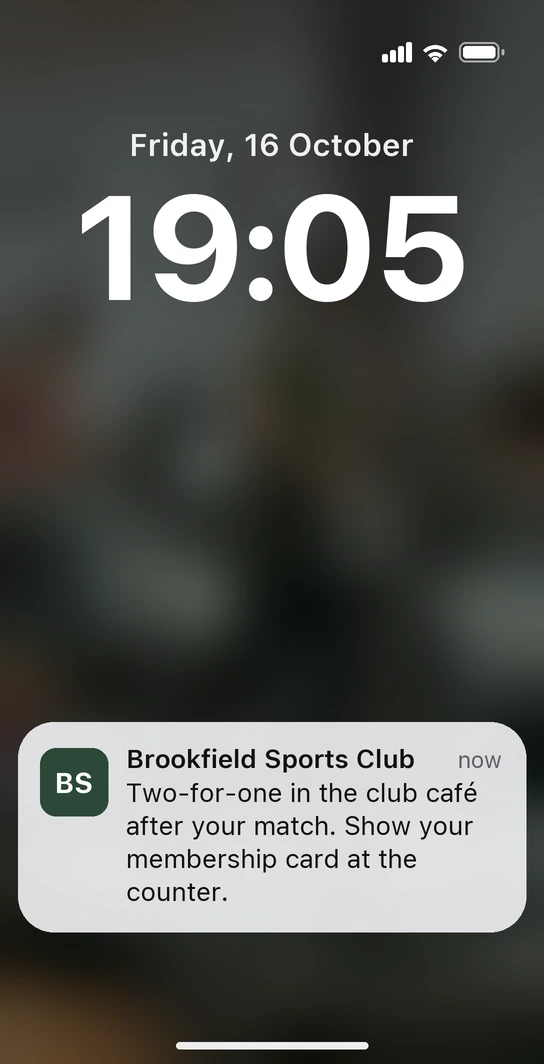 iPhone lock screen with a notification from Brookfield Sports Club's membership card: two-for-one in the club café after the match