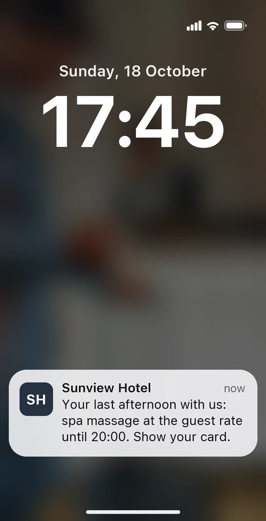 iPhone lock screen with a notification from Sunview Hotel's guest card: a spa massage at the guest rate on the last afternoon